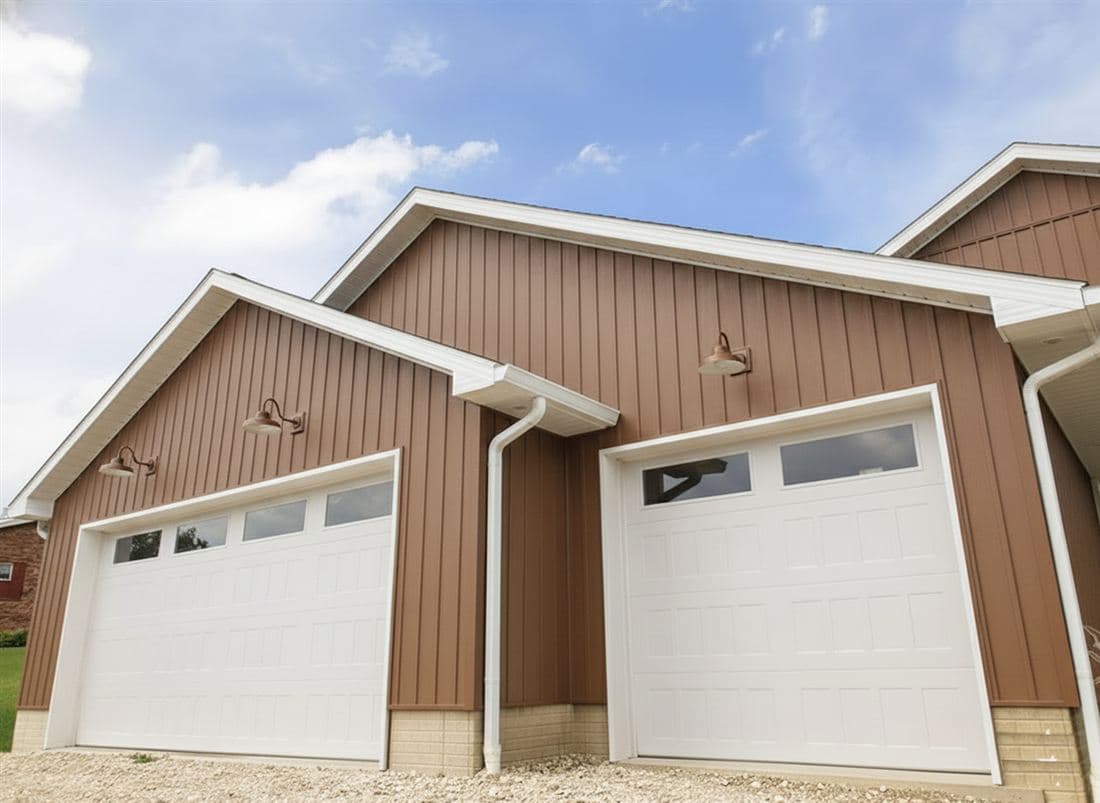 Two white garage doors on a brown sided garage