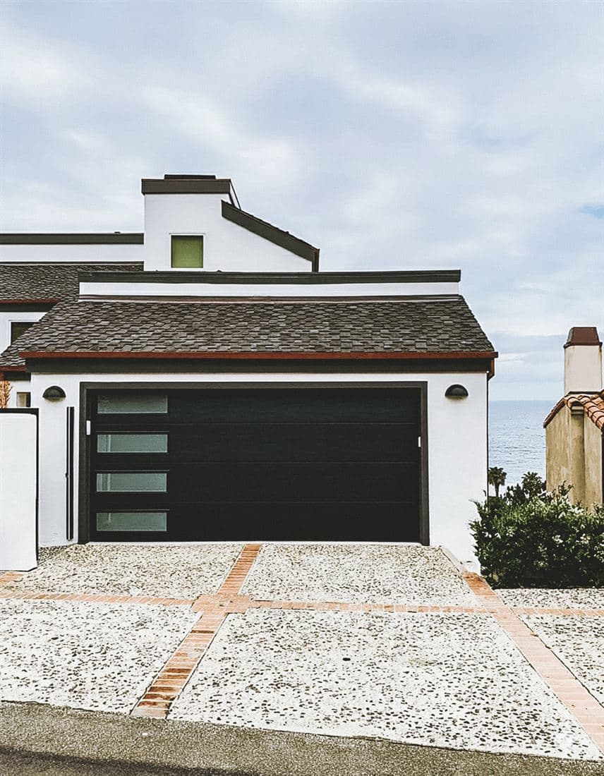 Black modern garage door with window slots on a stucco home